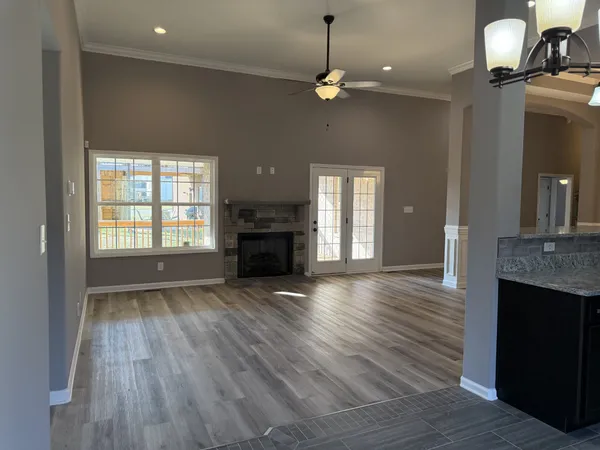 an empty room with wooden floor fireplace and windows