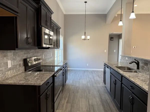 a kitchen with granite countertop a sink stove and cabinets