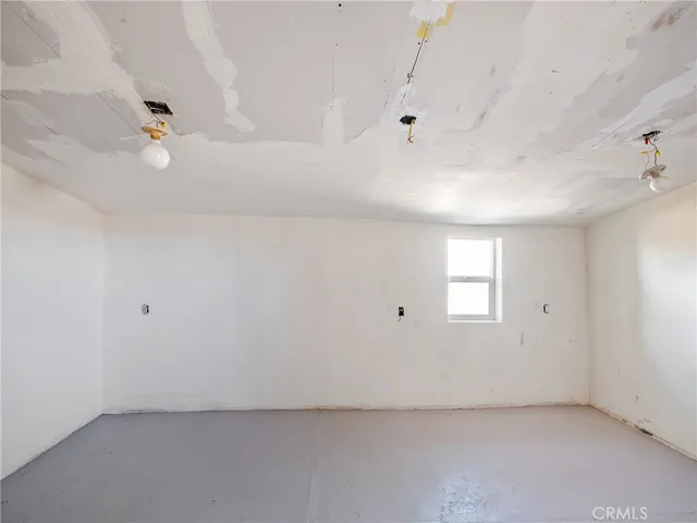 an empty room with a window and ceiling fan
