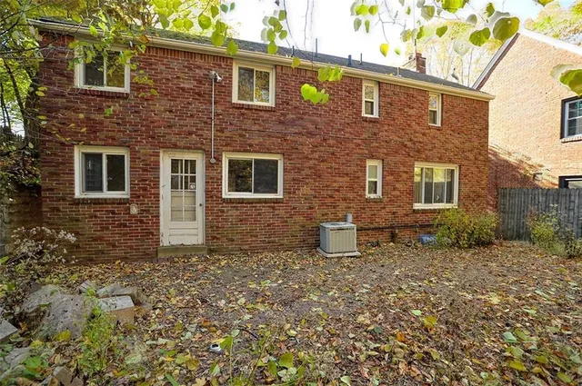a brick house that has a small yard and large trees
