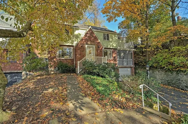 a view of a brick house next to a yard with plants and trees