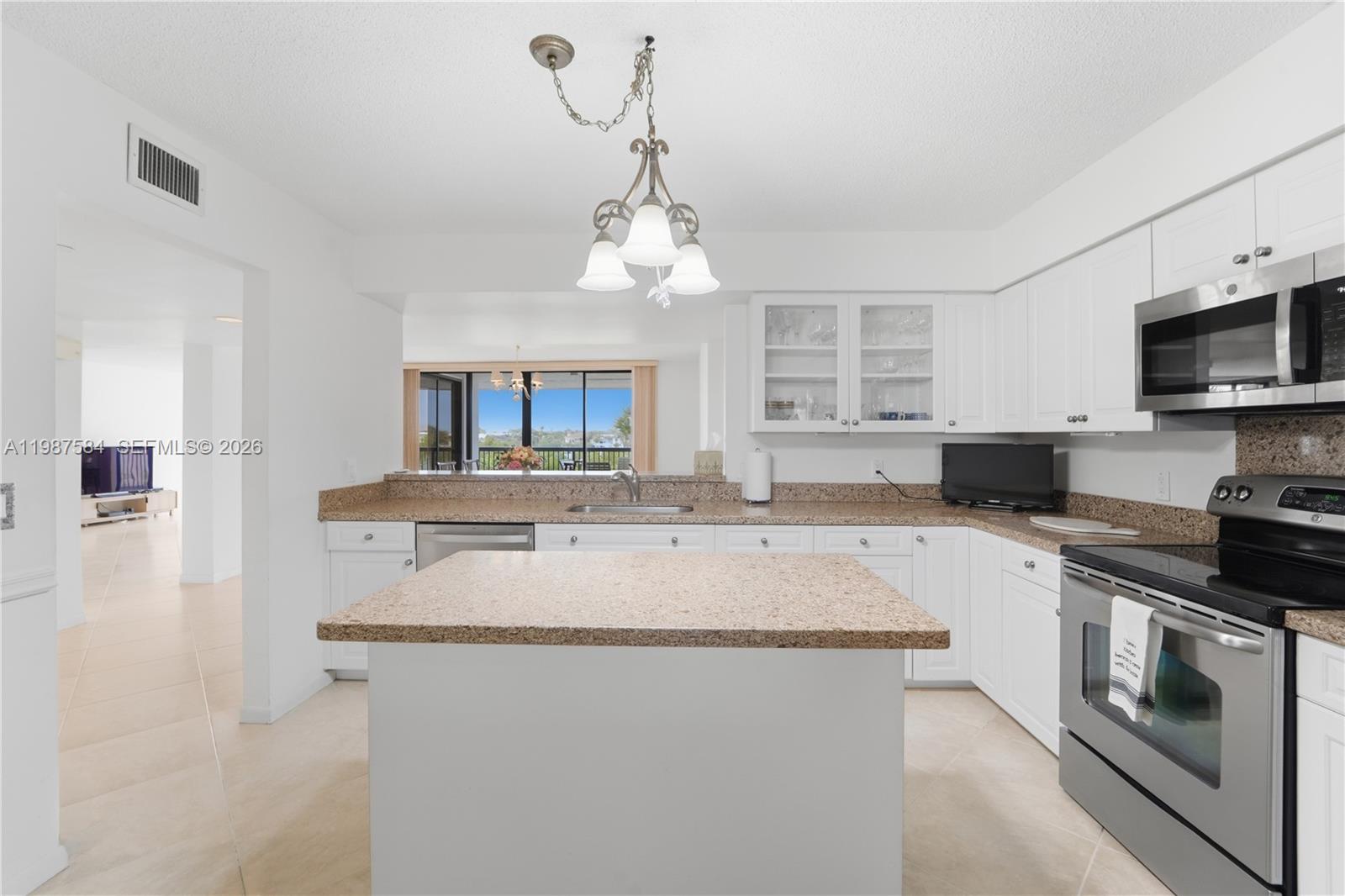 19670 South Beach Road, Unit B323 Tequesta, FL 33469 - Photo 14 of 57 a kitchen with stainless steel appliances granite countertop a stove sink and microwave