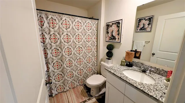 a bathroom with a granite countertop toilet sink and mirror
