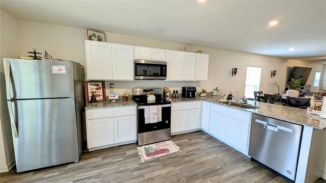 a kitchen with white cabinets stainless steel appliances and wooden floor