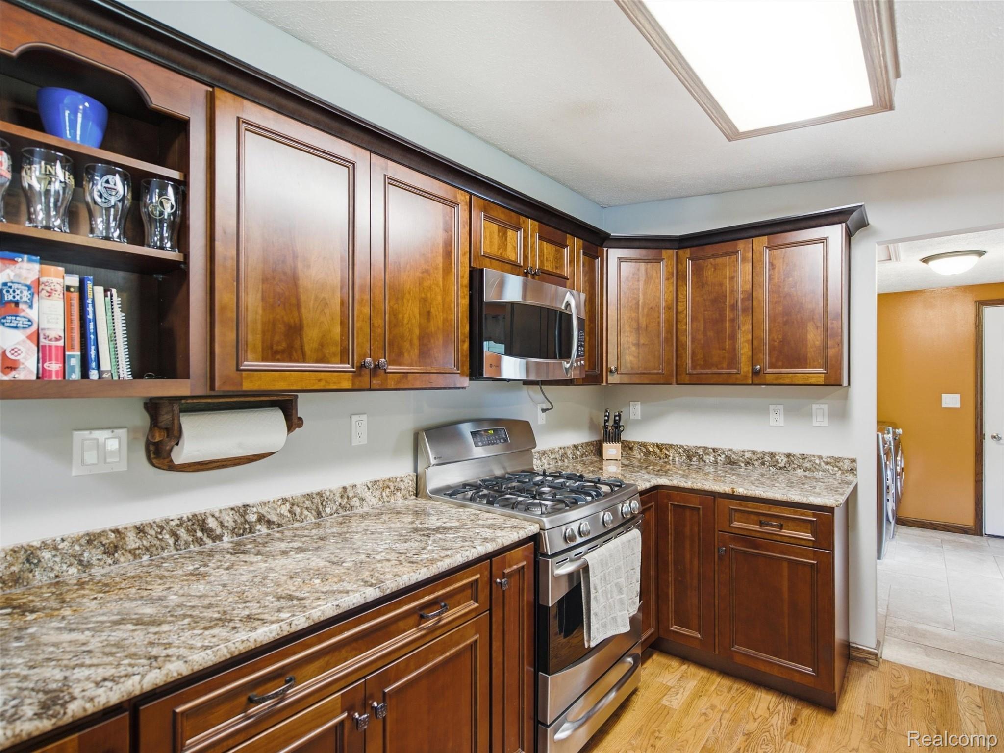 5003 Mason Road Howell, MI 48843 - Photo 13 of 59 Kitchen featuring wood-finish flooring, rich wood cabinetry with dark hardware, stone countertops, and stainless steel appliances