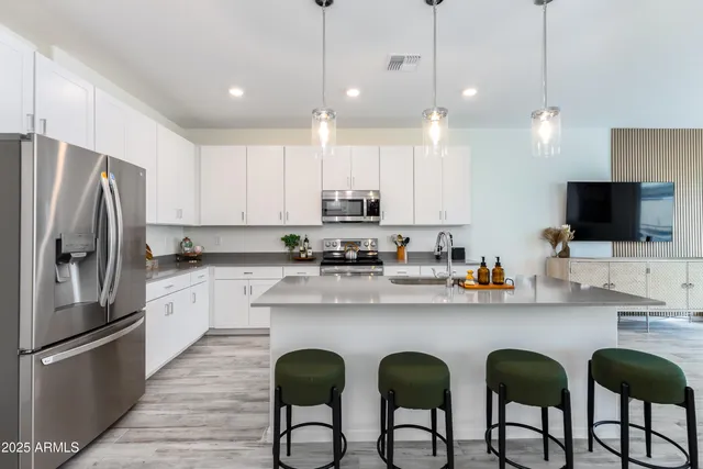 a kitchen with stainless steel appliances granite countertop a refrigerator a sink a stove a microwave and island with wooden floor