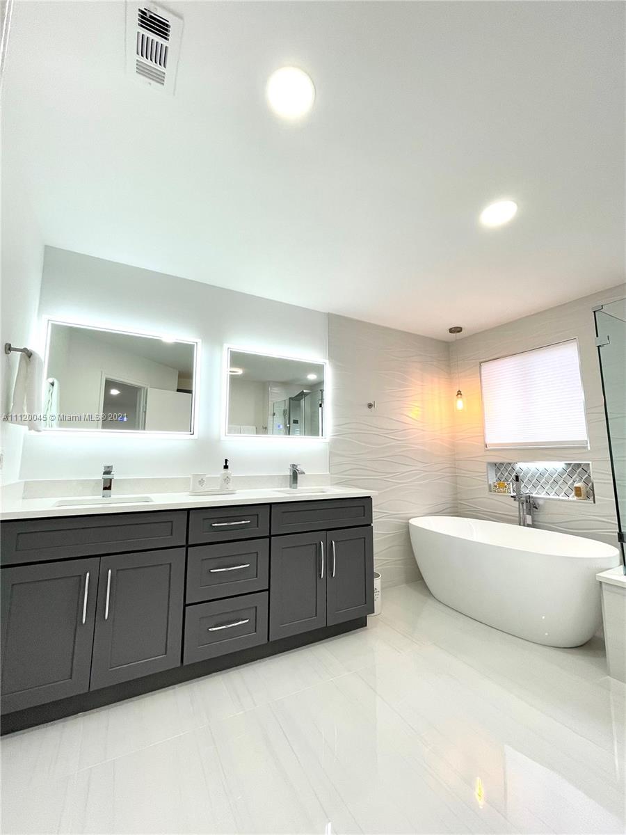 6726 Via Regina Boca Raton, FL 33433 - Photo 24 of 35 a spacious bathroom with a double vanity sink a large mirror and bathtub