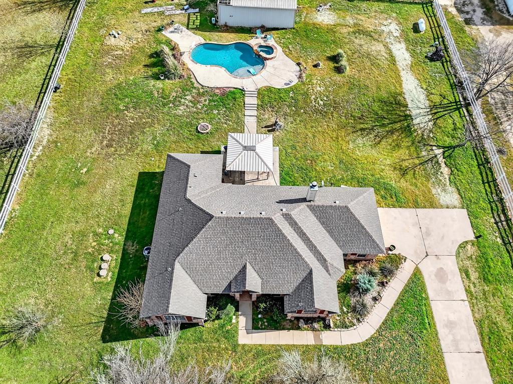 an aerial view of a house with swimming pool and large trees