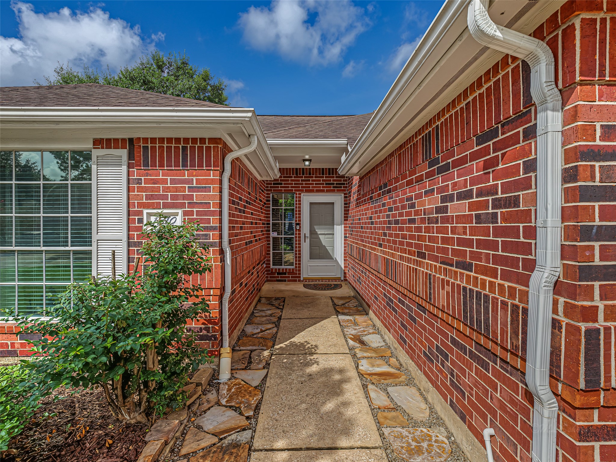 1310 Hidden Canyon Road Katy, TX 77450 - Photo 4 of 40 Charming brick entryway with a neatly paved path and lush greenery leading to the front door.