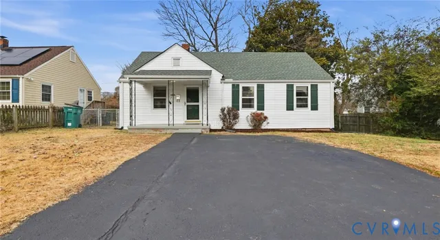 a front view of house with yard and trees in the background