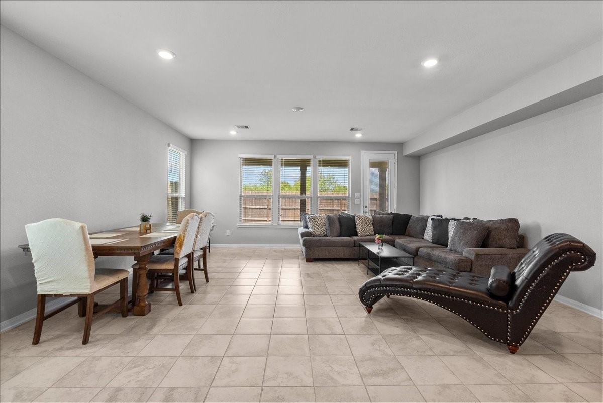 2320 Rosemary Street Rosenberg, TX 77469 - Photo 19 of 40 This spacious living area features a modern open concept with tiled flooring, a cozy sectional sofa, and ample natural light from large windows.