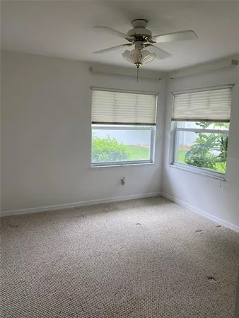 an empty room with windows and ceiling fan