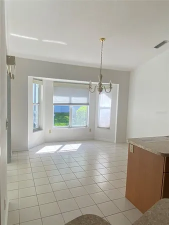a view of an empty room and window and chandelier fan