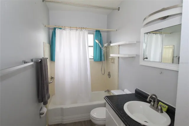 a kitchen with stainless steel appliances granite countertop a refrigerator a stove a sink and white cabinets with wooden floor