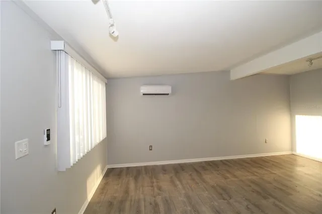 an empty room with wooden floor cabinet and windows