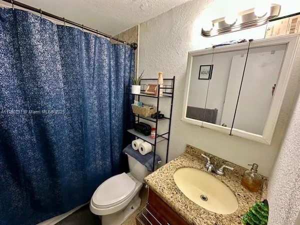 a bathroom with a sink a toilet and shower curtain