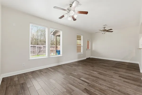 a view of an empty room with wooden floor and a window