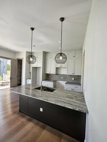 a kitchen with kitchen island granite countertop stainless steel appliances a sink a counter space and wooden floor