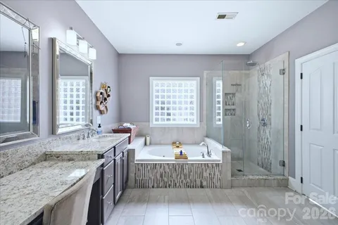 a bathroom with a granite countertop tub sink and mirror