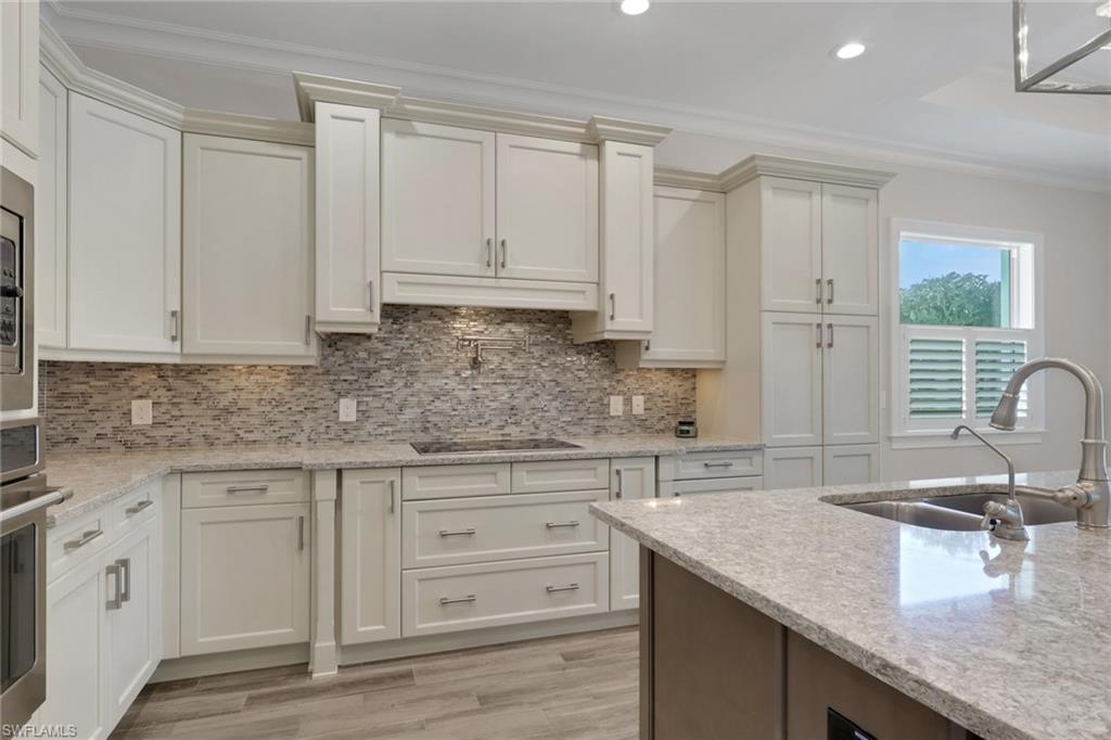 6482 Warwick Avenue Naples, FL 34113 - Photo 11 of 50 a kitchen with granite countertop a sink white cabinets and white appliances