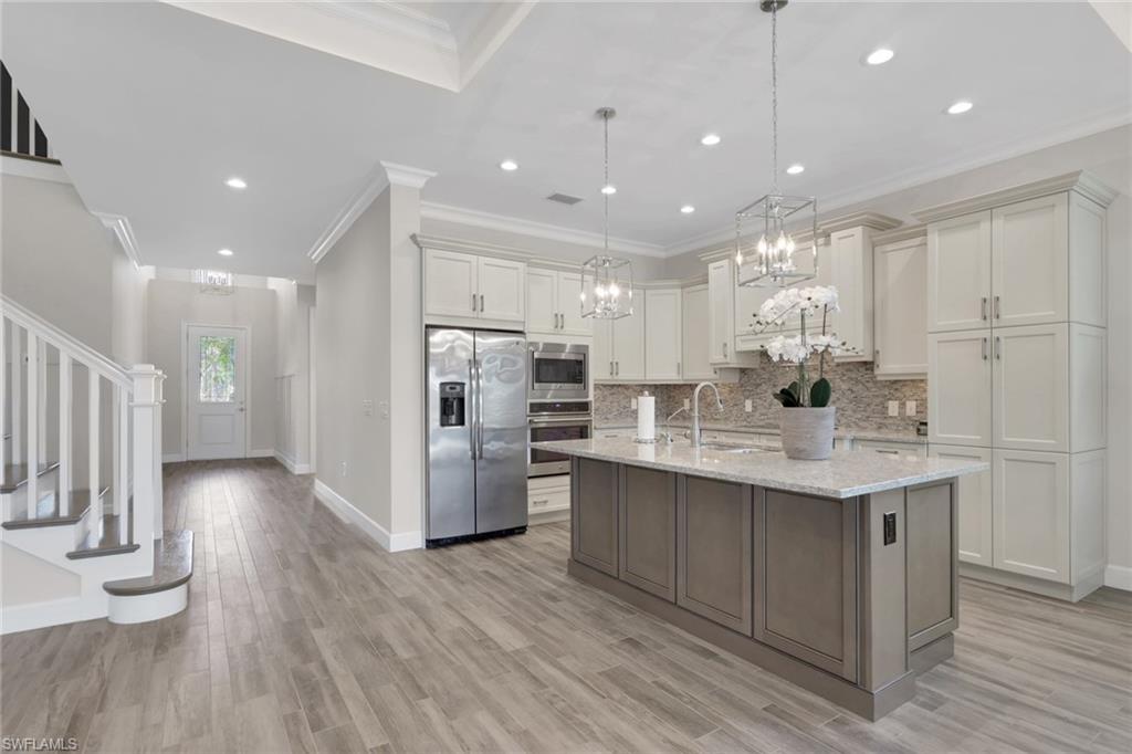 6482 Warwick Avenue Naples, FL 34113 - Photo 8 of 50 a kitchen with stainless steel appliances kitchen island hardwood floor sink and stove