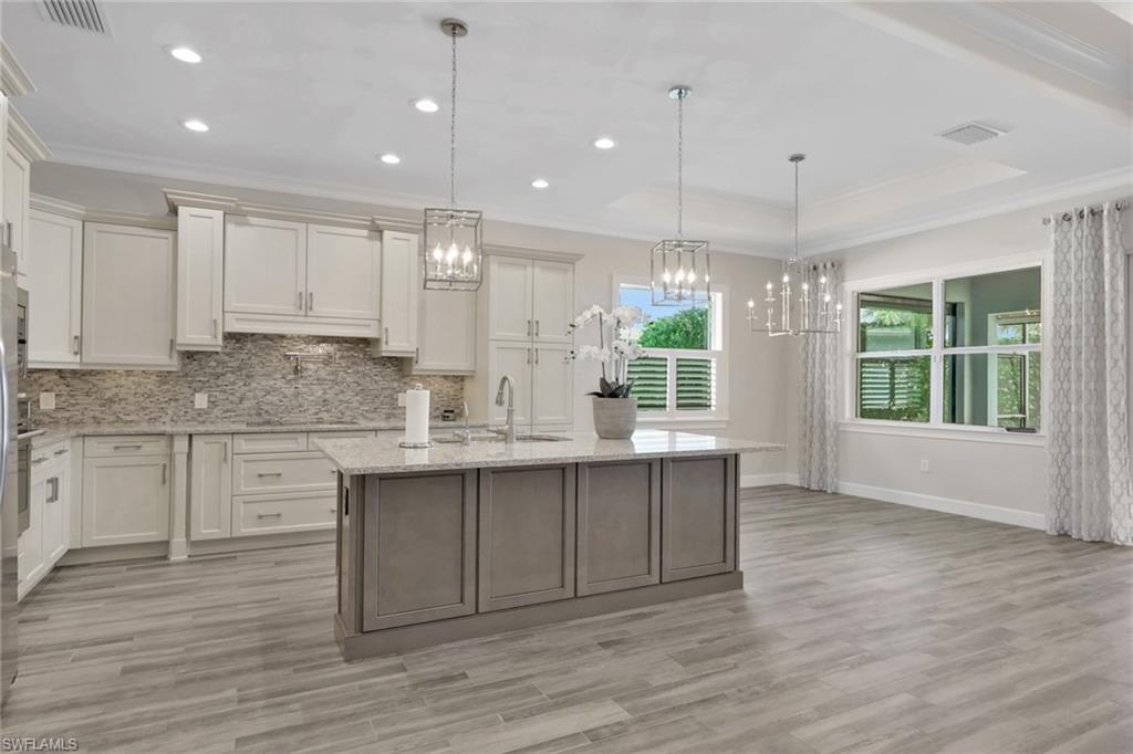 6482 Warwick Avenue Naples, FL 34113 - Photo 9 of 50 a kitchen with kitchen island granite countertop a sink cabinets and wooden floor