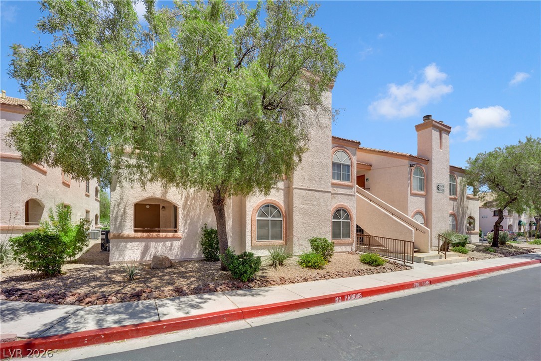 7570 West Flamingo Road, Unit 115 Las Vegas, NV 89147 - Photo 29 of 34 A terracotta-tiled roof crowns this multi-level residential building, accented by arched windows and desert landscaping.