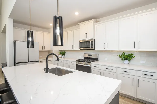 a kitchen with white cabinets a sink stove and refrigerator