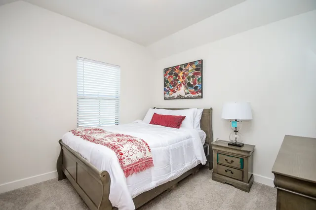 a bedroom with a bed and a lamp on dresser
