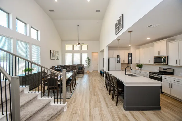 a view of a dining room and livingroom with furniture wooden floor a rug a painting and a chandelier
