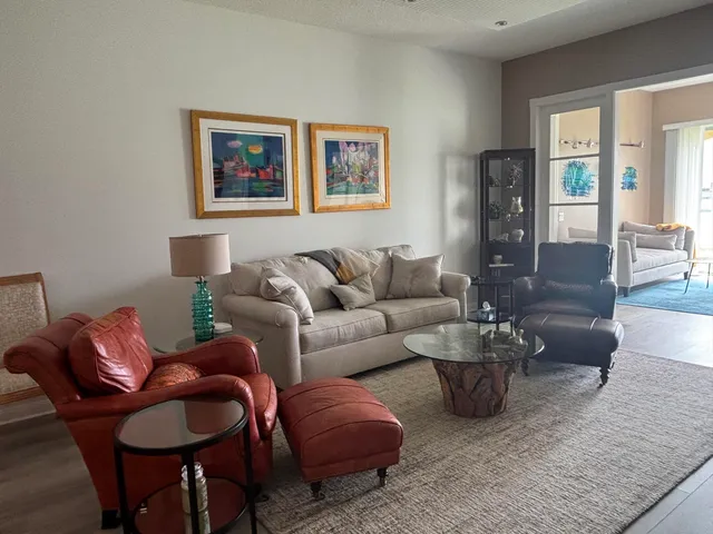 a living room with furniture potted plant and kitchen view