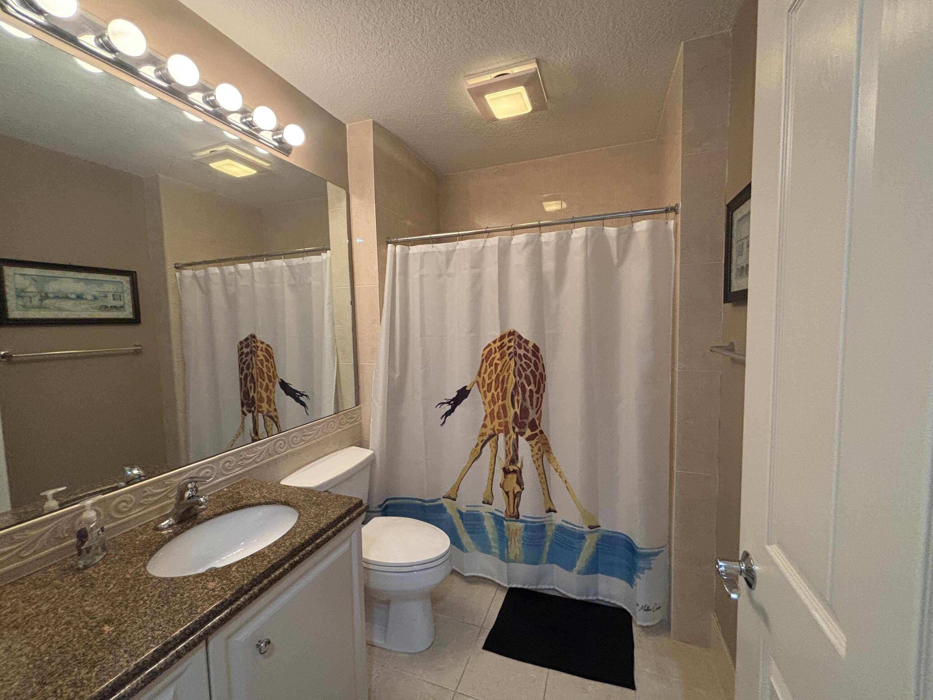 9 Harbour Isle Drive East, Unit 102 Fort Pierce, FL 34949 - Photo 27 of 30 a bathroom with a granite countertop sink toilet and shower