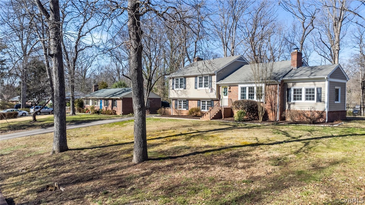 a view of a house with large tree and wooden fence