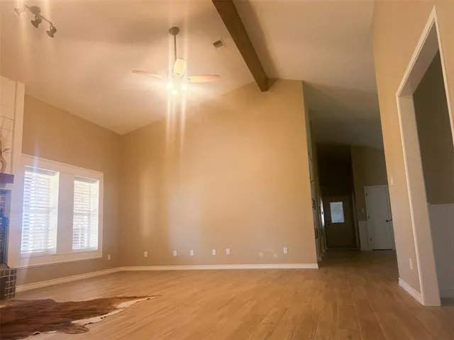 en empty room with windows and chandelier fan