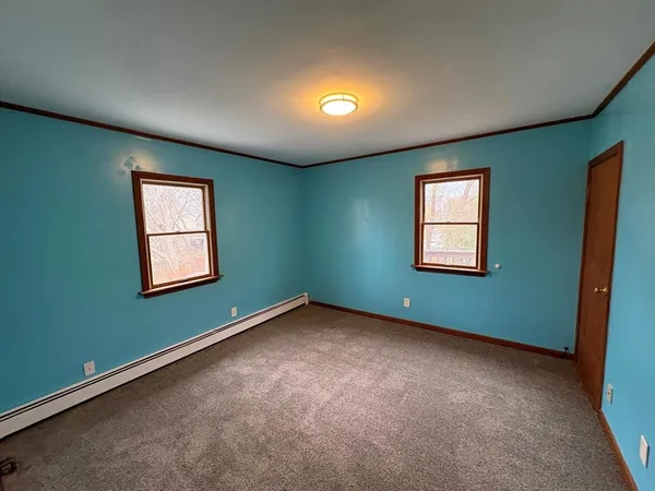 an empty room with chandelier fan and windows