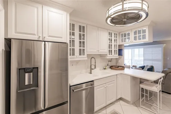 a kitchen with stainless steel appliances granite countertop a refrigerator a sink a stove and white cabinets with wooden floor