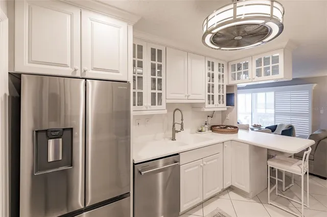 a kitchen with stainless steel appliances granite countertop a refrigerator a sink a stove and white cabinets with wooden floor