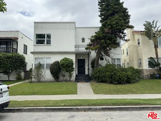 a front view of a house with a yard and potted plants
