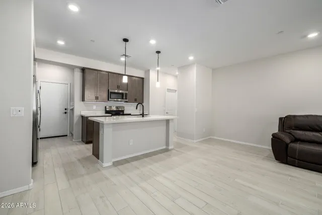 a view of kitchen with kitchen island stainless steel appliances refrigerator sink and cabinets