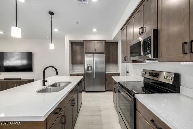 a kitchen with stainless steel appliances granite countertop a sink a stove and refrigerator