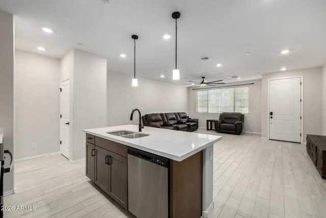 a large kitchen with a sink a counter top space stainless steel appliances and a ceiling fan