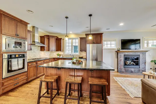 a kitchen with stainless steel appliances granite countertop a kitchen island a stove and a wooden cabinets