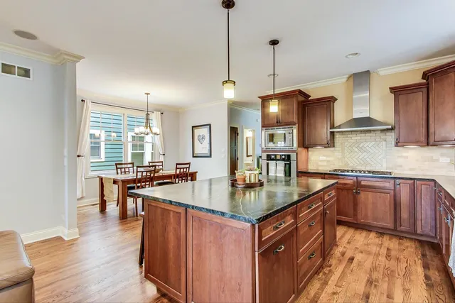 a kitchen with stainless steel appliances granite countertop a sink a stove top oven a counter space and living room view
