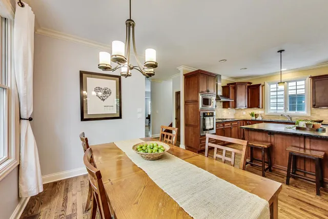 a dining room with stainless steel appliances kitchen island granite countertop a table chairs and a refrigerator
