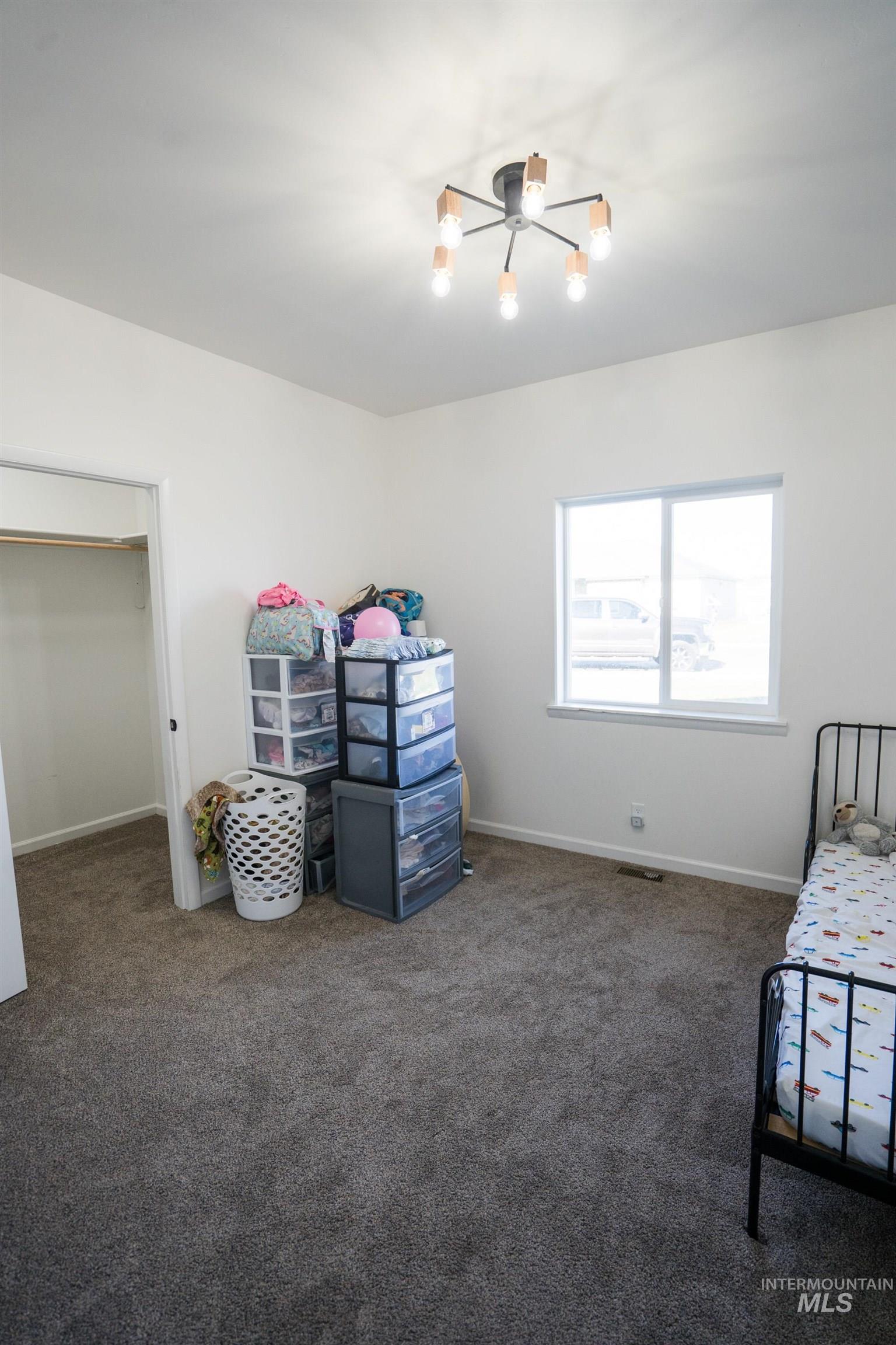 2110 Q Street Heyburn, ID 83336 - Photo 18 of 28 Unfurnished bedroom featuring carpet and a chandelier