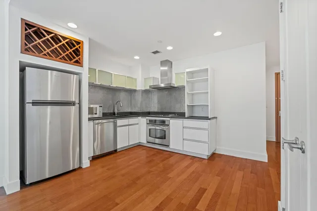 an empty room with wooden floor closet and windows