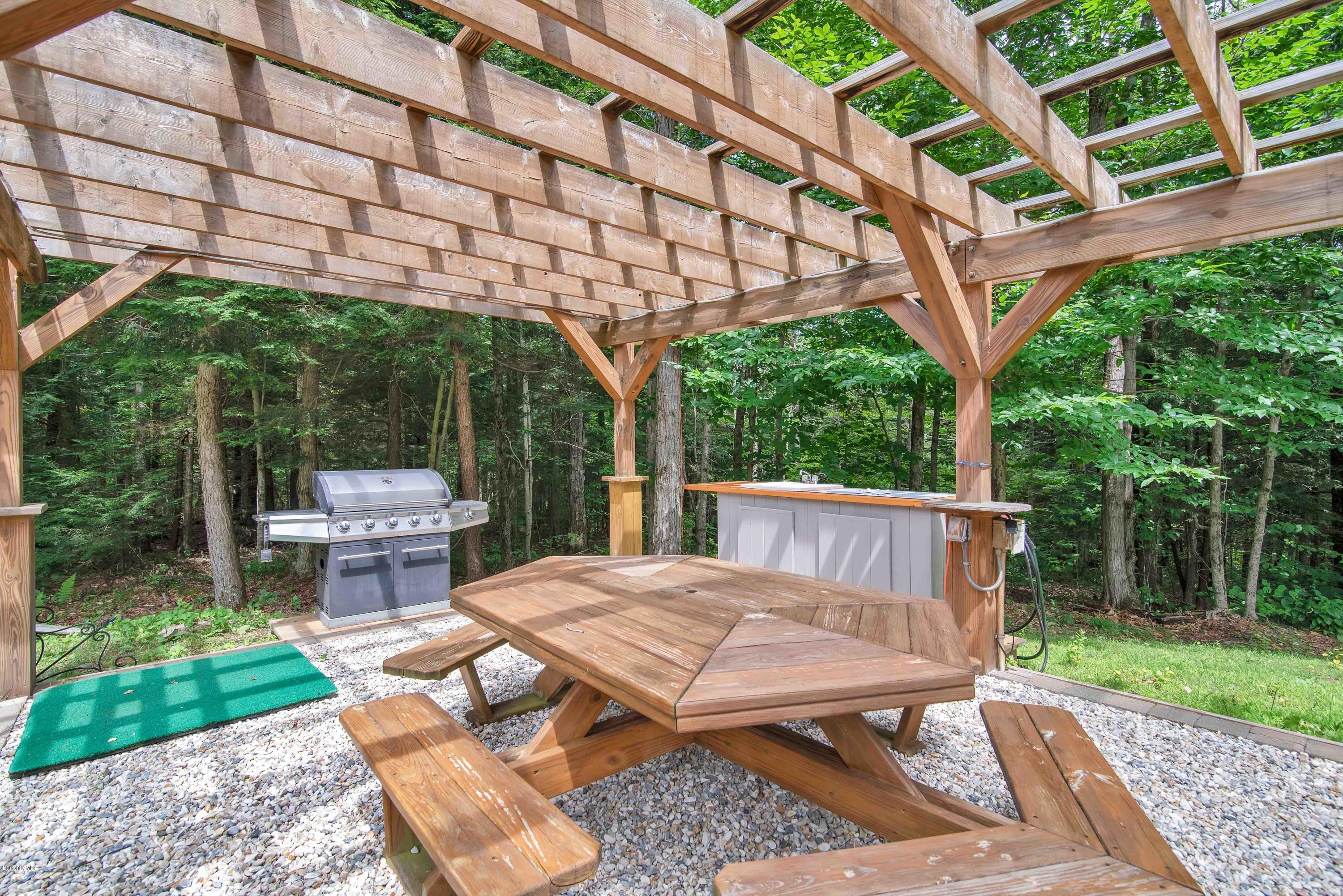 106 Dimmock Road Otis, MA 01253 - Photo 32 of 42 a view of backyard with a table and chairs under an umbrella with a large tree