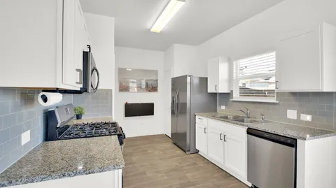 a kitchen with stainless steel appliances granite countertop a sink stove refrigerator and cabinets