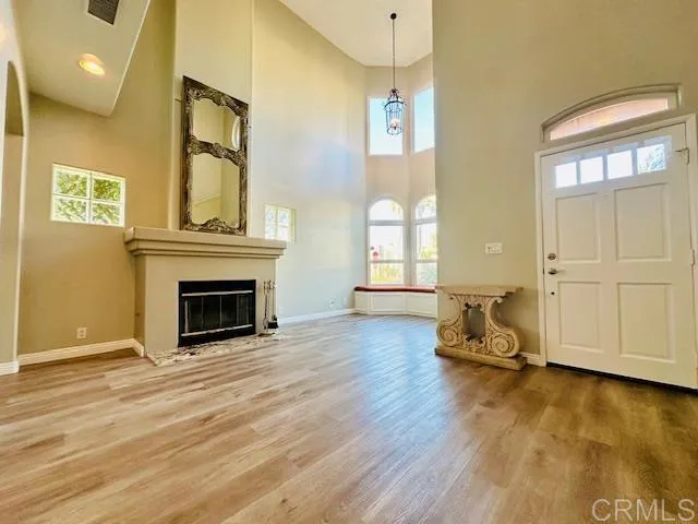 an empty room with wooden floor fireplace and windows