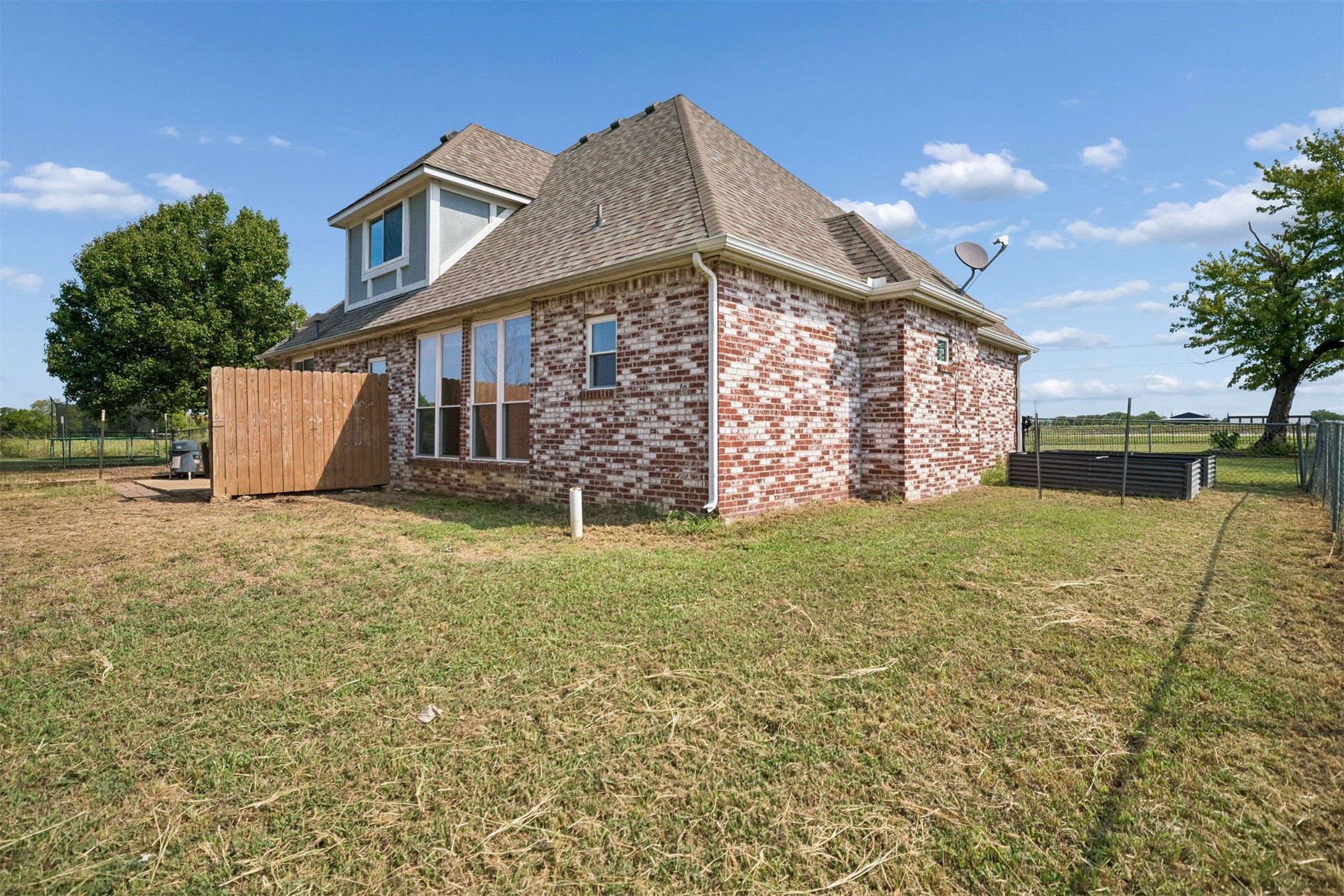 175 Alt 75 Mounds, OK 74047 - Photo 40 of 41 Brick exterior with a dormer, multiple windows, and a fenced yard with a raised planter box